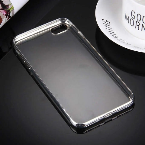 Transparent phone case with silver edges on black reflective surface near 'Good Morning' mug
