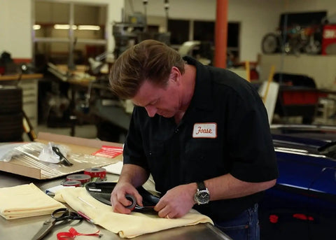 Person applying Super Strength Automotive Tape 03609 on a car part in a workshop setting.