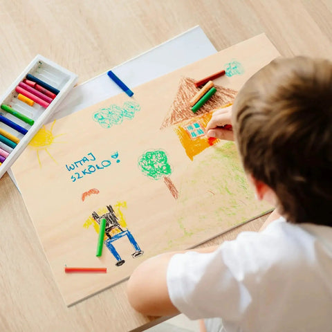 Child drawing on a basswood sheet with colored pencils, creating a colorful scene on a 12 Pack Basswood Sheets 12 X 16 X 3mm Thick Unfinished Basswood For Laser Cutting And Engraving Crafts Painting Wood Burning Architectural Models DIY Projects And Easy To Cut For Precise Results.