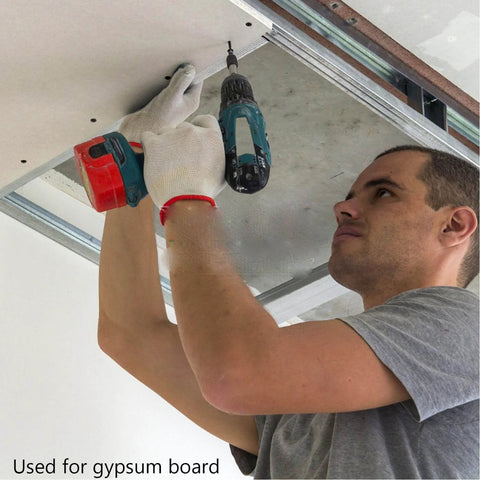 Man installing gypsum board with drill wearing gloves, showing use for Wood Screws Kit 250 Piece High Hardness Flat Head Wood Screws Set With Phillips Drive Assorted Sizes 6 By 1-3/8, 6 By 1-3/16, 6 By 1, 6 By 25/32, 6 By 5/8 Black Finish Built Tough For DIY Furniture Decks And General Woodworking.