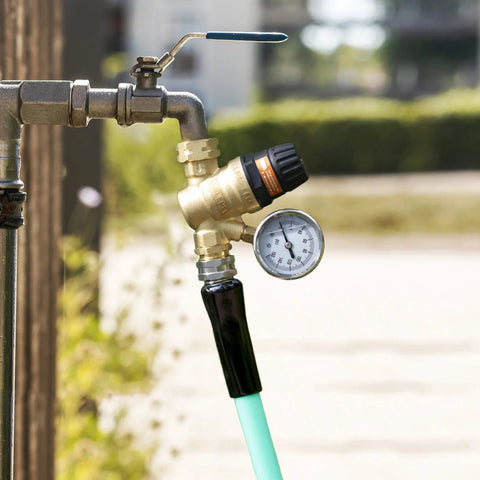 Brass RV water pressure regulator with adjustable handle and dial gauge, 3/4 inch connector, hose attached.