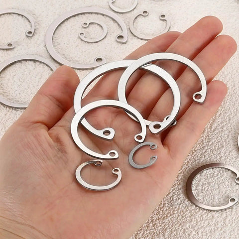 A hand holding 50 Pcs 16.6mm Inner Retaining Ring Circlip 304 Stainless Steel Snap Rings C Clips GB893 For Grooved Shafts Studs.