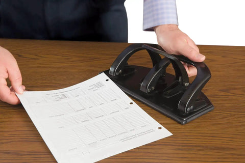 Man using 20-Sheet Duo Two-Sided Heavy-Duty Hole Punch that switches between two and three holes like a boss instantly, on a wooden desk.