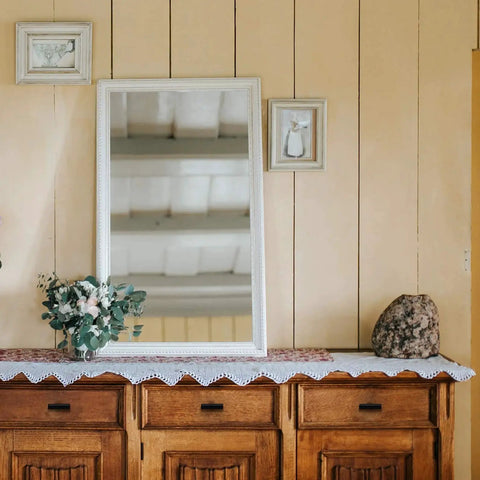 Decorative wooden dresser with mirror and plants, reflecting rustic interior design style.