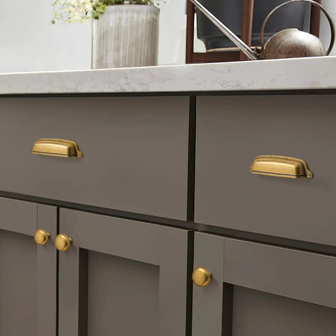 10 Pack 3 Inch Antique Brass Cup Pulls With Aged Gold Finish installed on kitchen drawer, vintage brass hardware shown in use.