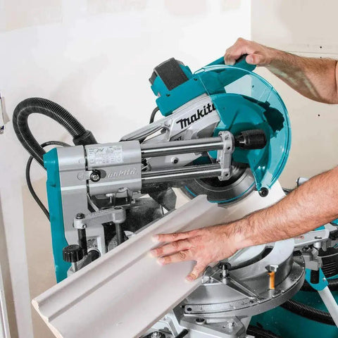 Close-up of Makita LS1019L 10 Inch Dual Bevel Sliding Compound Miter Saw with Laser cutting wood trim, showing crown molding capacity.