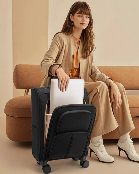 Woman placing laptop in black Airline Approved 22x14x9 Carry On Luggage With Spinner Wheels LOVEVOOK Lightweight Softside Suitcase.