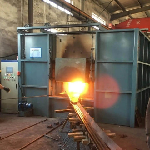 Image of a heavy-duty industrial forging machine with a glowing hot metal piece being processed inside a factory setting.