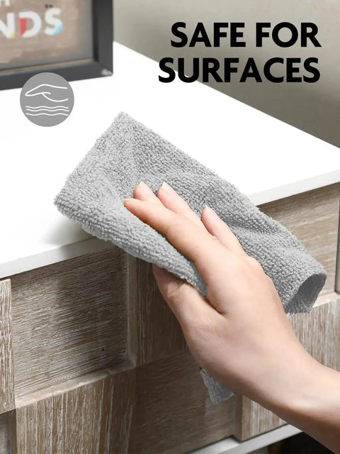 Hand using grey Ultra Absorbent Microfiber Cloth Roll Tear Away Towels 12x12 Pink Grey Reusable on a surface