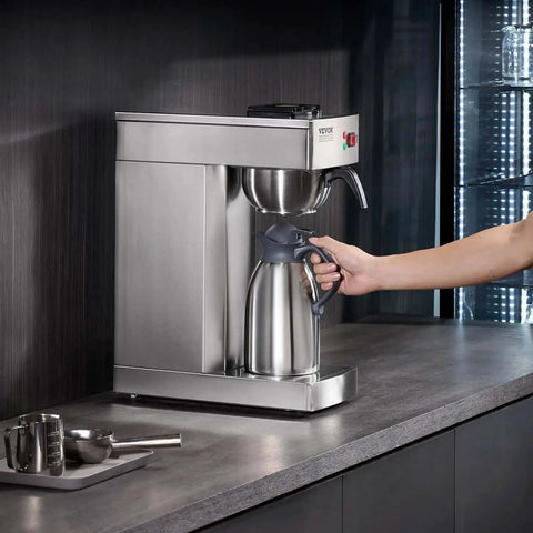 Person using 12 Cup Commercial Drip Coffee Maker With Thermal Vacuum Carafe Keeps Coffee Hot Or Cold All Day No Fuss For Restaurant Office Cafe Stainless Steel Brewer That Brews A Full Pot In About 9 Minutes on countertop.