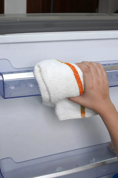 Person using a 60 Pack 16 By 19 Inch Terry Bar Mop Rag for Cleaning Absorbent and Durable Cotton Cloths on a kitchen appliance.