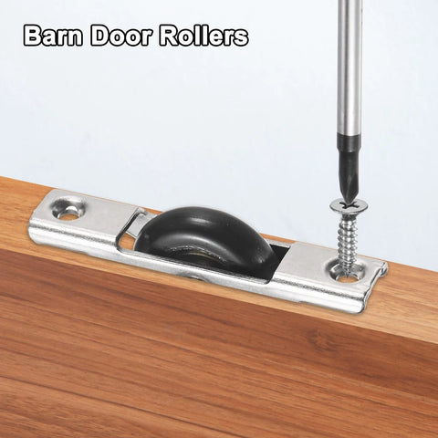 Installation of barn door roller on wooden surface with screwdriver, showing metal bracket and black wheel sliding mechanism.