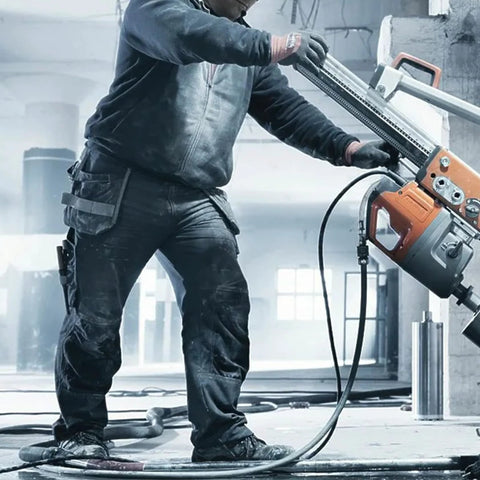 HVAC vacuum hose, black, attached to orange and gray high-flow evacuation unit in an industrial workshop.