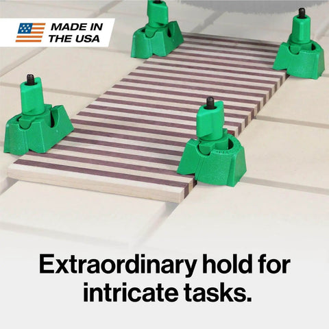 Matchfit U-Pad Low Profile Clamp System holding a striped board on CNC table for woodworking, showing secure grips on corners.