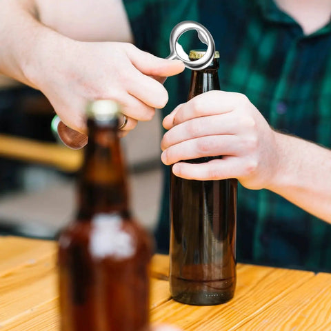 Person using a bottle opener from Bulk 15 Piece Metal Bottle Opener Kit With Zinc Alloy Inserts For DIY Wood Turning And Craft Projects Perfect For Valentines Day Weddings Wine Parties And Party Favors to open a beer bottle