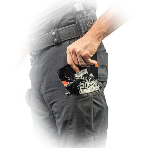 Person placing IPOK Compact First Aid Kit With C A T Tourniquet Gauze And Gloves By North American Rescue in BDU pocket.