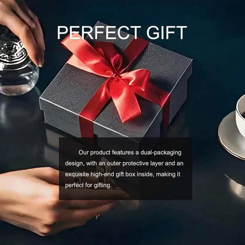 Black gift box with red ribbon, hand holding water glass, perfect gift text, cup and saucer on dark tabletop.