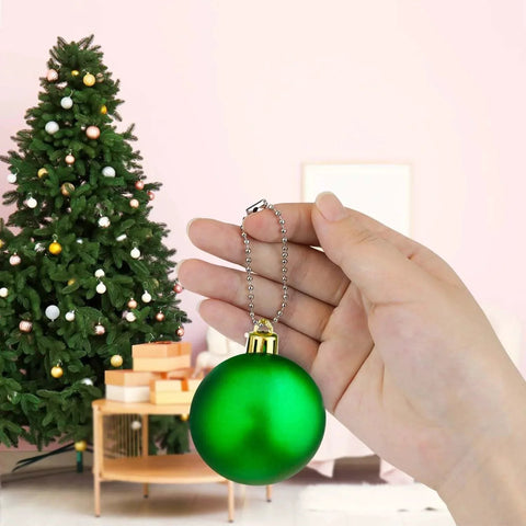 Person holding a green ornament with 100 Pcs Ball Bead Chain Keychain Dog Tag Metal Bead Chain, Christmas tree in background.