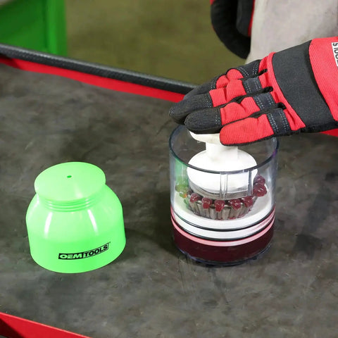 Gloved hand using Bearing Packer For Wheel Bearings Up To Three And A Half Inch Diameter With Transparent Grease Cup on workbench