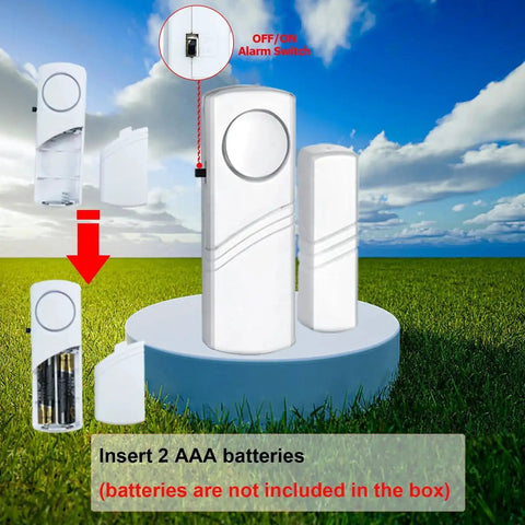 Loud Wireless Door And Window Alarm Pack displaying unit with battery insertion guide and alert switch in open field view.