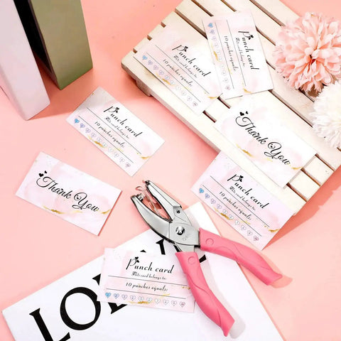 Heart Shaped Handheld Punch Card Kit With 100 Reward Cards, Single Hole Paper Puncher in Durable Metal with soft grip on a pink table