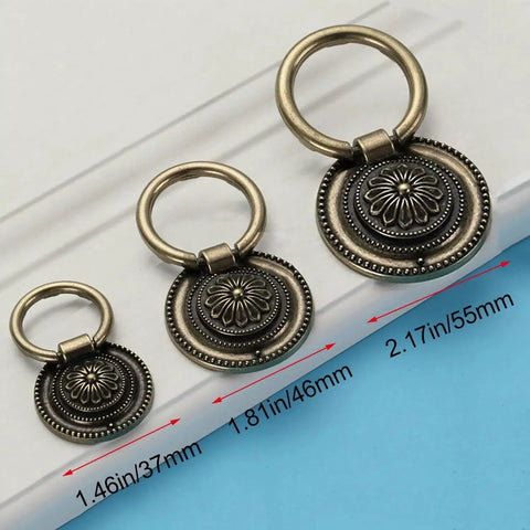 Three vintage oil rubbed bronze ring pulls in antiqued copper color, floral pattern, displayed on a surface with size measurements.