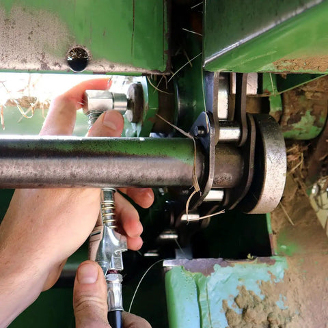 Person using 90 Degree Grease Coupler Adapter For Tight Spaces With Spring Loaded Collar And Three Hardened Steel Jaws Rubber Seal And Check Valve Delivering A Tight Reliable Connection In Hard To Reach Fittings From LockNLube on machinery