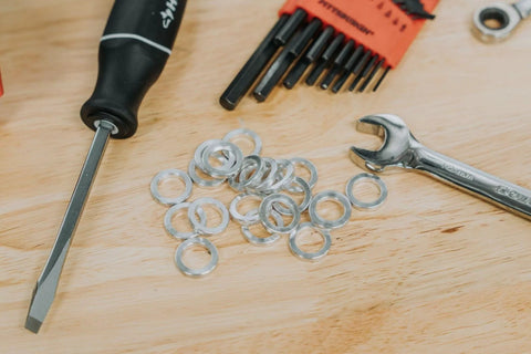 Silver round steel spacers scattered on a wooden workbench