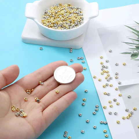 Hand holding 2000 Pcs Gold And Silver Spacer Beads 4Mm Flat Round Disc Beads for DIY Jewelry with a coin for scale