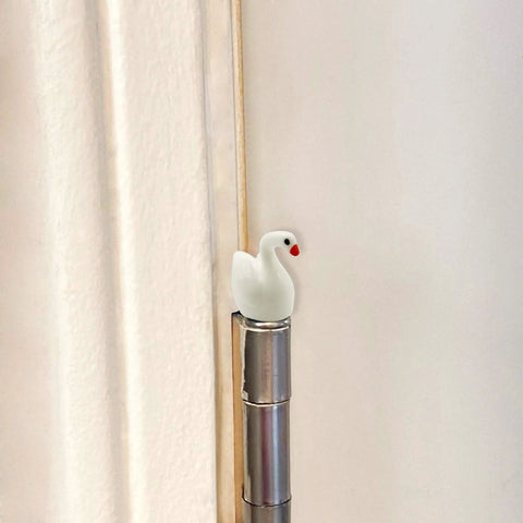 Whimsical Mini Swan Hinge Head Magnets Set Of 6 For Door Decor And Metal Surfaces installed on a door hinge pin.