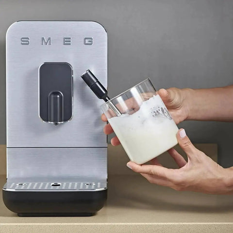 Person frothing milk next to Fully Automatic Coffee Machine With Steam For Home Use Black BCC12BLMUS Six Drink Options