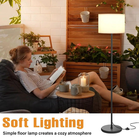 60 Inch Black Floor Lamp With White Shade And Foot Pedal Switch For Living Room next to a person reading in a cozy setting.