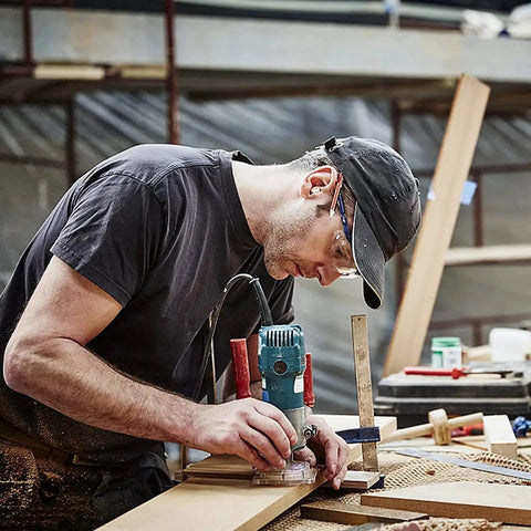 Woodworker using a router to cut edges with a 45 Degree Chamfer Router Bit Set for Smooth Angled Edges, focusing on precision work.