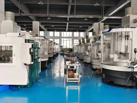 Interior of a manufacturing facility with rows of CNC machines on a blue floor.