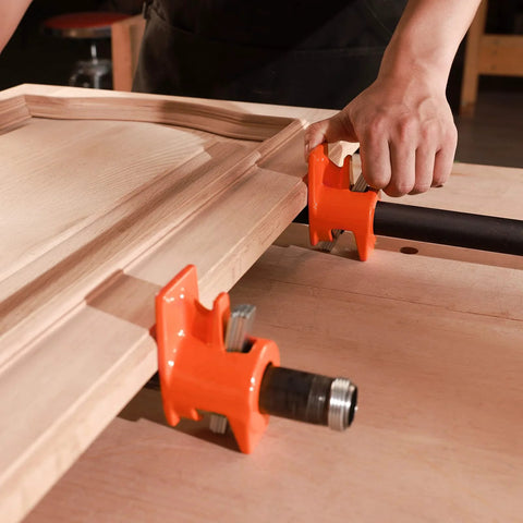Two orange PONY wood-gluing pipe clamp fixtures for 3/4 inch black pipe, securing a wooden panel.
