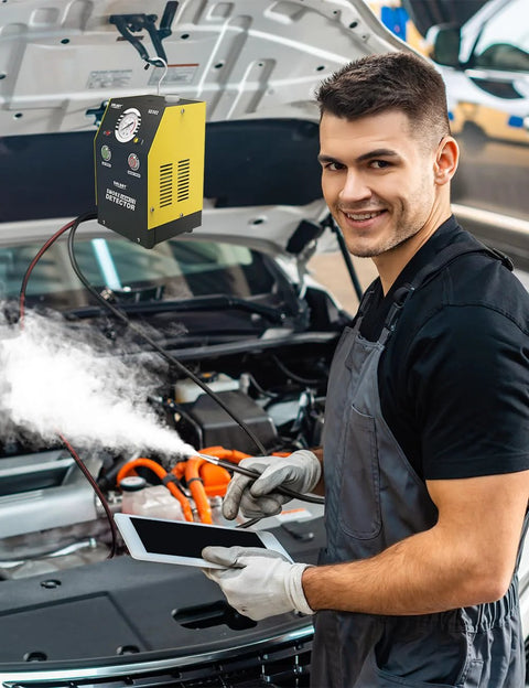 Solary automotive smoke tester, yellow/black, hanging by open hood; mechanic uses tablet while smoke vents into engine bay.