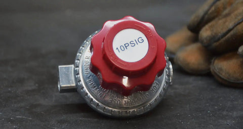 Close-up of 0-10 Psi Adjustable Propane Regulator For Smokers And Turkey Fryers, red knob, UL Listed, on black surface, focus keyword