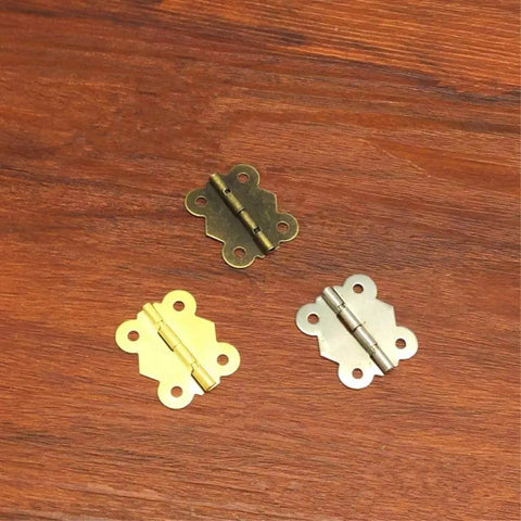 Gold, silver, and bronze miniature butterfly hinge set for dollhouses and tiny boxes 29mm x 27mm shown on wood surface.