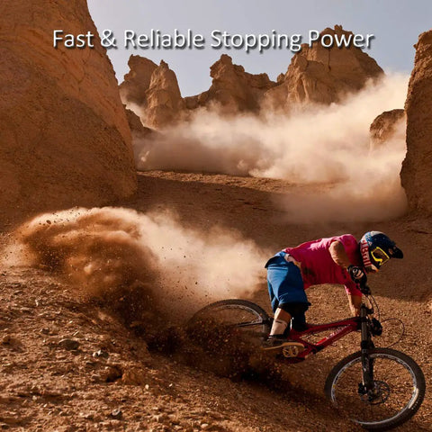Side view mountain biker in pink shirt on red bike navigating dusty desert trail among rocky formations, helmeted rider.