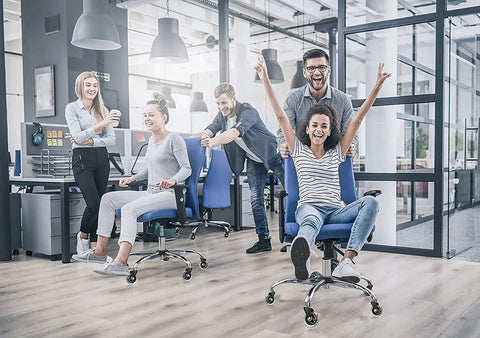 Group of people having fun in an office, using desk chairs with heavy duty rubber chair casters 3 inch replacement wheels.