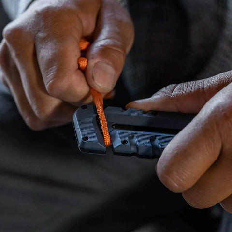 Person using Prybrid 8 In 1 Multi Tool Knife With Wire Stripper Bottle Opener Pocket Clip to cut cord, close-up view.