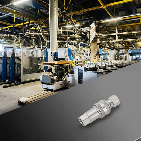 Hydraulic quick connector M14, silver metal quick-disconnect coupler on gray surface with factory machinery background.