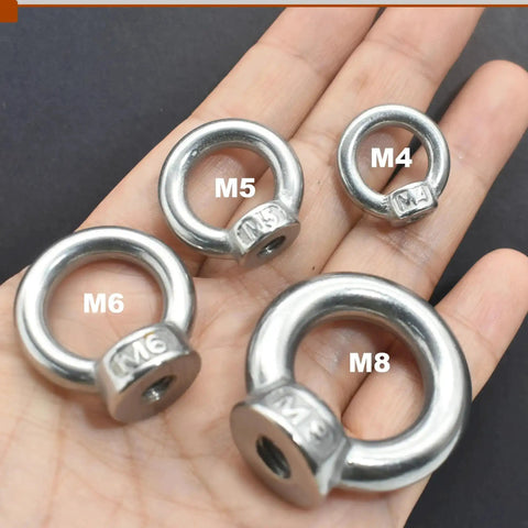 Hand holding M4, M5, M6, M8 lifting eye nuts in varying sizes with clear markings on a black background
