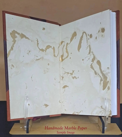 Open leather-bound book, front view, cream and gold marbled endpapers.