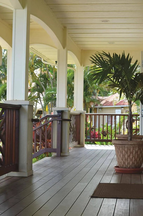 Covered porch with wooden decking, potted plant, and railing, showcasing a cozy outdoor living space.