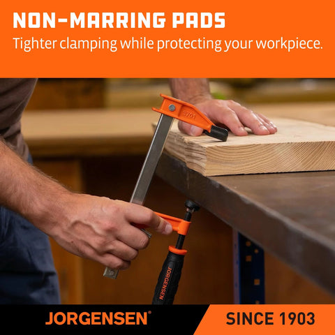 Jorgensen orange steel bar clamp securing a wood plank to a workbench; hand tightening the clamp