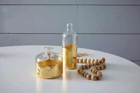 Glass bottles with gold leafing on table, showcasing finish using Mona Lisa Water Based Sealer For Metal Leafing Projects By Speedball Clear Fast Drying Sealant That Prevents Tarnish And Will Not Yellow 2 Ounces Pro Grade Finish