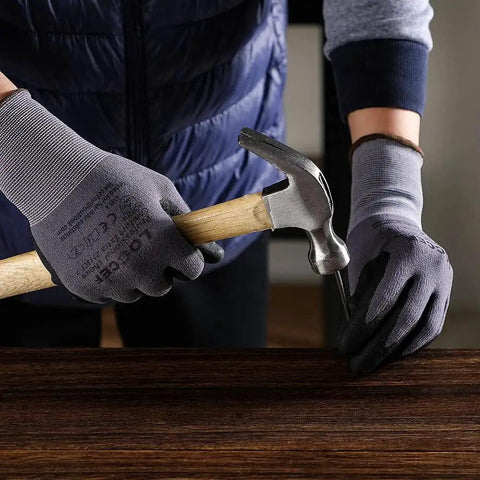 Person wearing MicroFoam Nitrile Coated Work Gloves 12 Pairs Size M Seamless Knit Nylon Grip while using a hammer on wood surface.