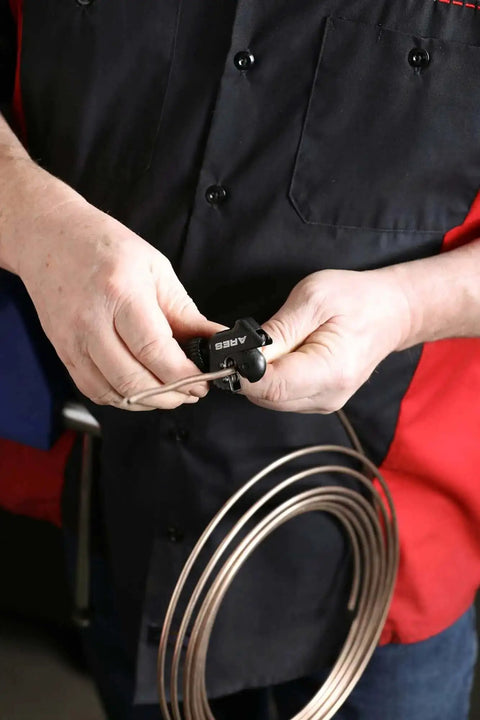 Close-up of a person using a mini tubing cutter from the Heavy Duty Double Flaring Tool Set With Extra Adapters For Copper Aluminum Soft Steel Brake Lines And Brass Tubing Comes With Mini Tubing Cutter And Case Quarter Inch Five Sixteenths Inch Half Inch Three Sixteenths Inch And Three Eighths Inch Adapters.