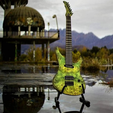 Electric guitar with green finish on stand outdoors beside a dome structure and mountains in the background.